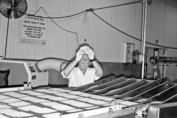 An employee removes broken matzo from a machine at the Manischewitz Company plant on Avenue K in Newark, N.J., on Tuesday, August 2, 2016.