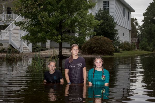 Kai Schuman, (left) Hana Schuman (center) and Kipper Case (right) pose for a portrait in front of a damaged neighborhood home which was flooded due to storm surge from Hurricane Florence in Washington, North Carolina on September 15, 2018.