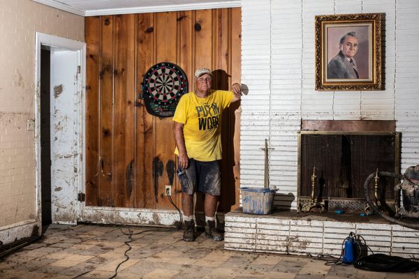 Dr. Sam Quillen Jr.'s poses for a portrait next to a painting of his father at his property, which was a dentist's office as well as residential housing, that was destroyed by floodwaters in Neon, K.Y., on Friday, August 5, 2022.