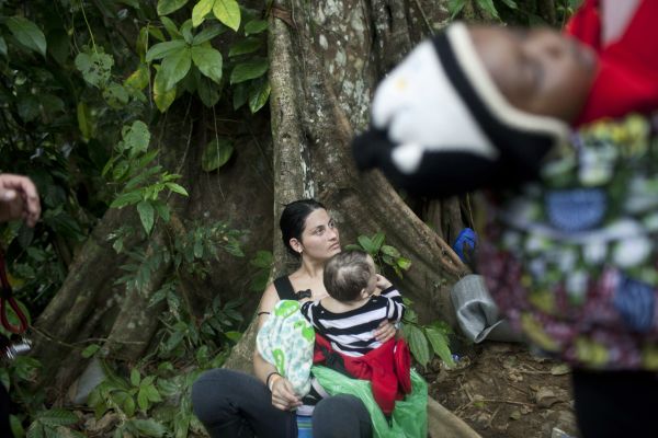 Veruzca, a migrant from Venezuela, rests with her baby while David, a 7 months old toddler, is carried away by his mother, Rabi, Darien gap, Colombia, September 11, 2022.