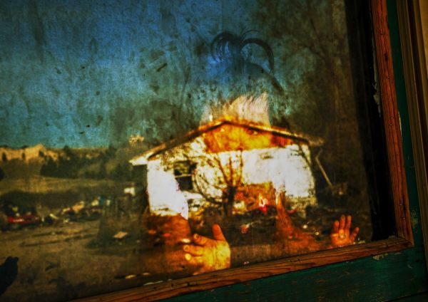 Serset, two year old Native American Sioux, looks onto outside, as the desolate town of Manderson in the Pine Ridge reservation is reflected on the window.