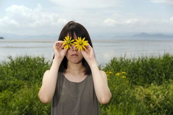 Fu, Japanese lady, poses with wild daisy, in Fukushima, where she has the family root.