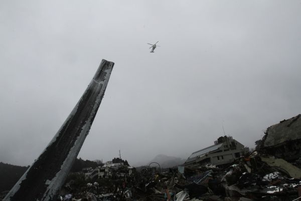 The destroyed village scene of Onagawa due to the unprecedented tsunami in Japan, created by the March 11th magnitude 9 earthquake, while a Japanese Navy copter is flying.