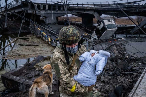 A Ukrainian soldier carries a baby across a destroyed bridge on the outskirts of Kyiv, Ukraine on March 3. 2022.