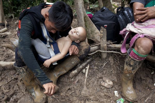An Embera indigenous guide, takes a rest while carrying a baby who was given to him, by the boy's mother (unseen) through a steep mountain, Panama, October 27, 2021.