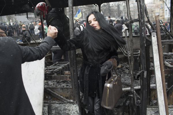 A young woman steps off a destroyed vehicle that was used to form a barricade between demonstrators and police forces during a lull in violent clashes between demonstrators and police forces on Hrushevsky Street in central Kyiv, January 21, 2014.