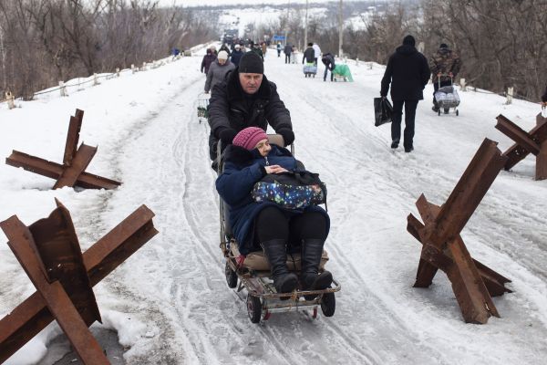 A man pushes an elderly woman on a sled toward a Ukrainian State Border Guard Service crossing point from Russian supported separatist held territory into Ukrainian controlled territory in Stanytsia Luhanska, located approximately 850 km east of the Ukrainain capital Kyiv (Kiev).