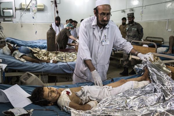 A male nurse works to stabilize a boy who was seriously injured in the bombing of the Afghan bank in Jalalabad.