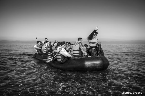 A rubber dinghy carrying several dozen migrants and refugees, mainly from Afghanistan, Syria, Iraq and Iran, approaches a rocky beach of Lesbos island.