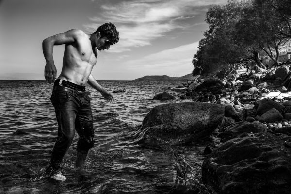 A young migrant man emerges from the sea after he jumped from his rubber dinghy and swam the last 30 meters to the shore.