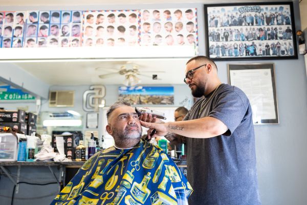 Barber Jhonny Chingas gives Pablo Molina a haircut at Sixteenth Street Barber Shop in National City, California.