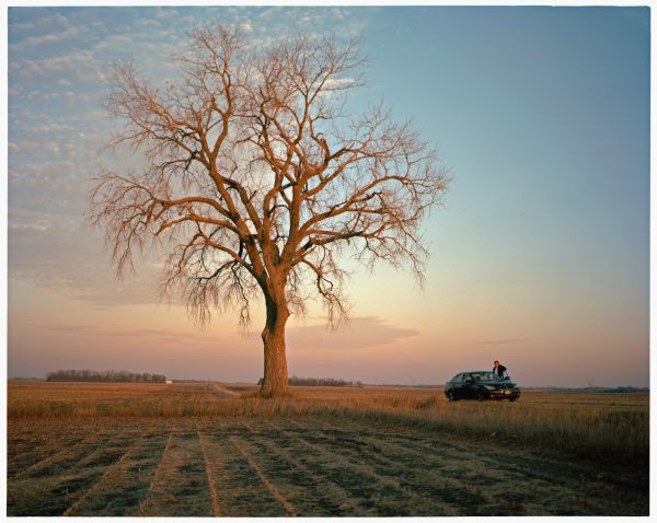 Garrison Keillor standing outside his car on road heading west from the Twin Cities.