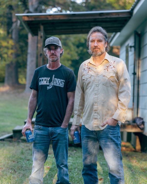 Portrait of Michael Foster Smith and Shane Brown (the son of Larry) drinking a beer on the property where The Shack is located.