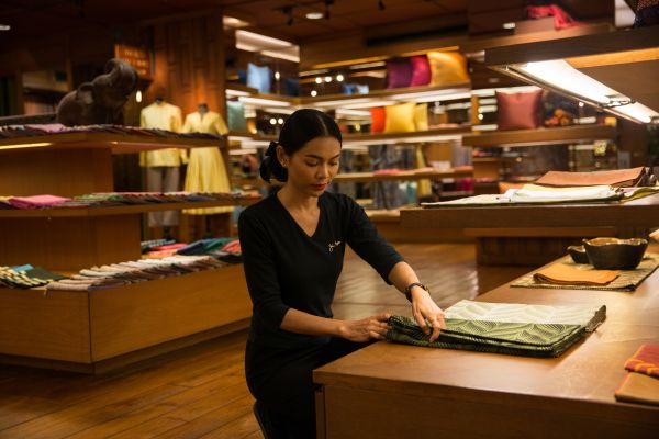 A shop assistant re-arranges silk products at the Jim Thompson flagship store in central Bangkok.