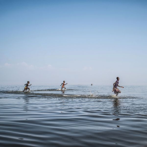 Children play and swim along the shore of Lake Turkana, Kenya.