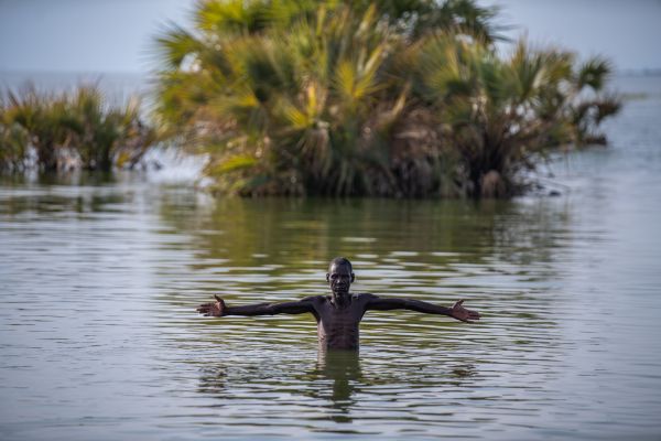A fisherman raises his arms as he emerges from Lake Turkana outside Kalokol town, on August 8, 2020.
