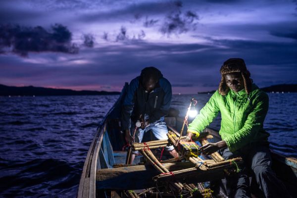 Fisherman Andrew Odongo Omollo, an Asobo electric motor customer, and crewman Michael Okoth, prepare battery-powered lanterns before floating them one by one in the waters of Lake Victoria, in Mbita, Kenya, on May 10, 2021.