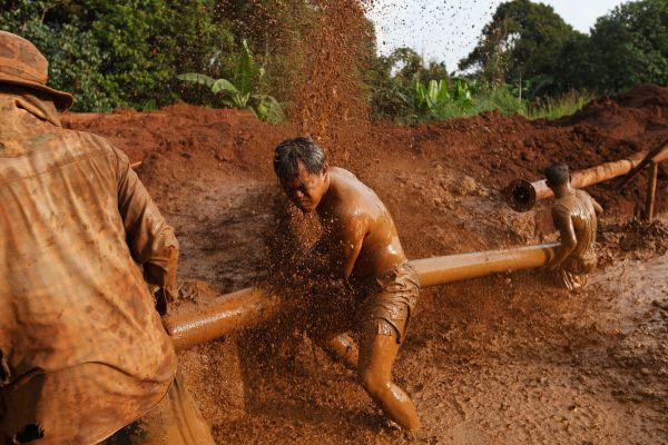 Workers repair a water pipe in a drainage reservoir adjacent to a large gem mine just outside the town of Chantaburi.