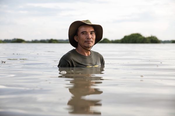 A man who's land was flooded by a dam constructed nearby stands in what was previously farmland. Si Saket, Thailand.