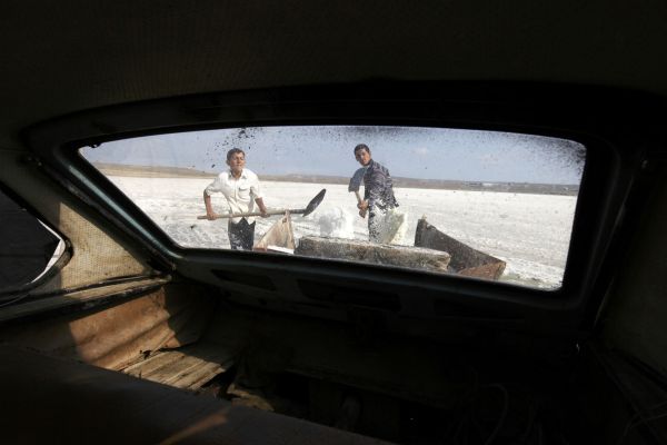 Two brothers shovel salt from Lake Binagadi in to a trailer attached to the back of their old Soviet-era car.