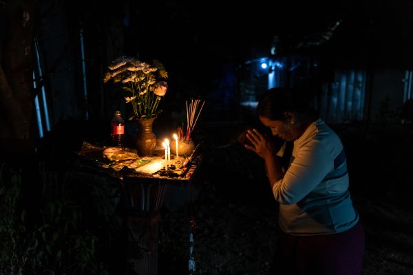 A Burmese migrant worker prays at a Buddhist shrine inside their workers camp.