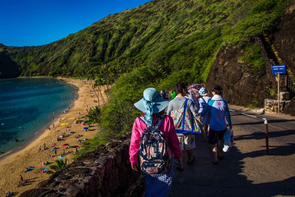 Visitors to Hanauma Bay Nature Preserve walk toward the beach on the Island of Oʻahu in the Hawaii Kai neighborhood of East Honolulu, in the Hawaiian Islands.